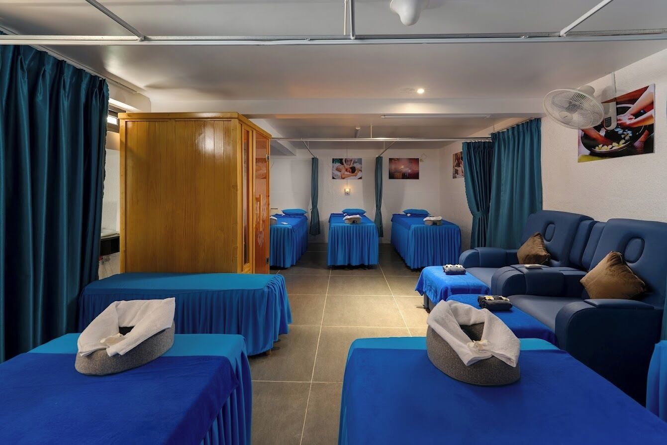 A room with multiple beds, a sofa, and a fan.