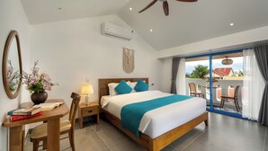 A hotel room with a large bed, a desk with a chair, a lamp, a mirror, and a view of the outside balcony. - The Linh Coastline Villa (Da Nang)