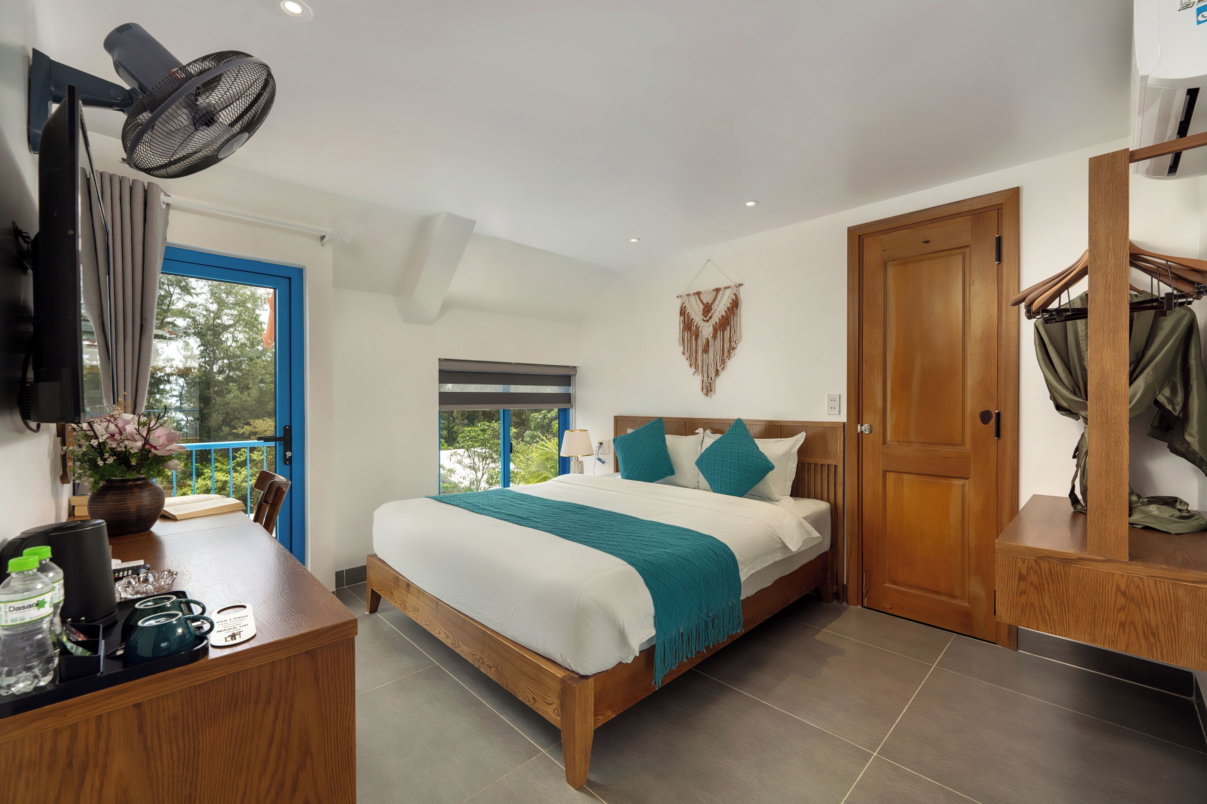A bedroom with a bed, bedside table, TV, and a window with curtains.