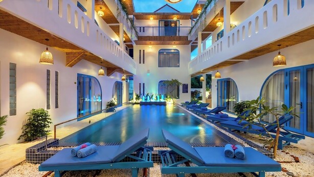 A pool area with lounge chairs and a central water feature. - The Linh Coastline Villa (Da Nang)