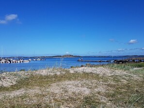 A coastal scene with boats docked at a pier, a sandy beach, and a clear blue sky. - 4 Star Holiday Home in Asa (Åsa)
