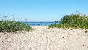 Une plage de sable fin, avec un ciel bleu clair et une mer calme.
