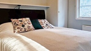 A neatly made bed with floral-patterned pillows and a plain headboard. - 4 Star Holiday Home in Orno (Orno)