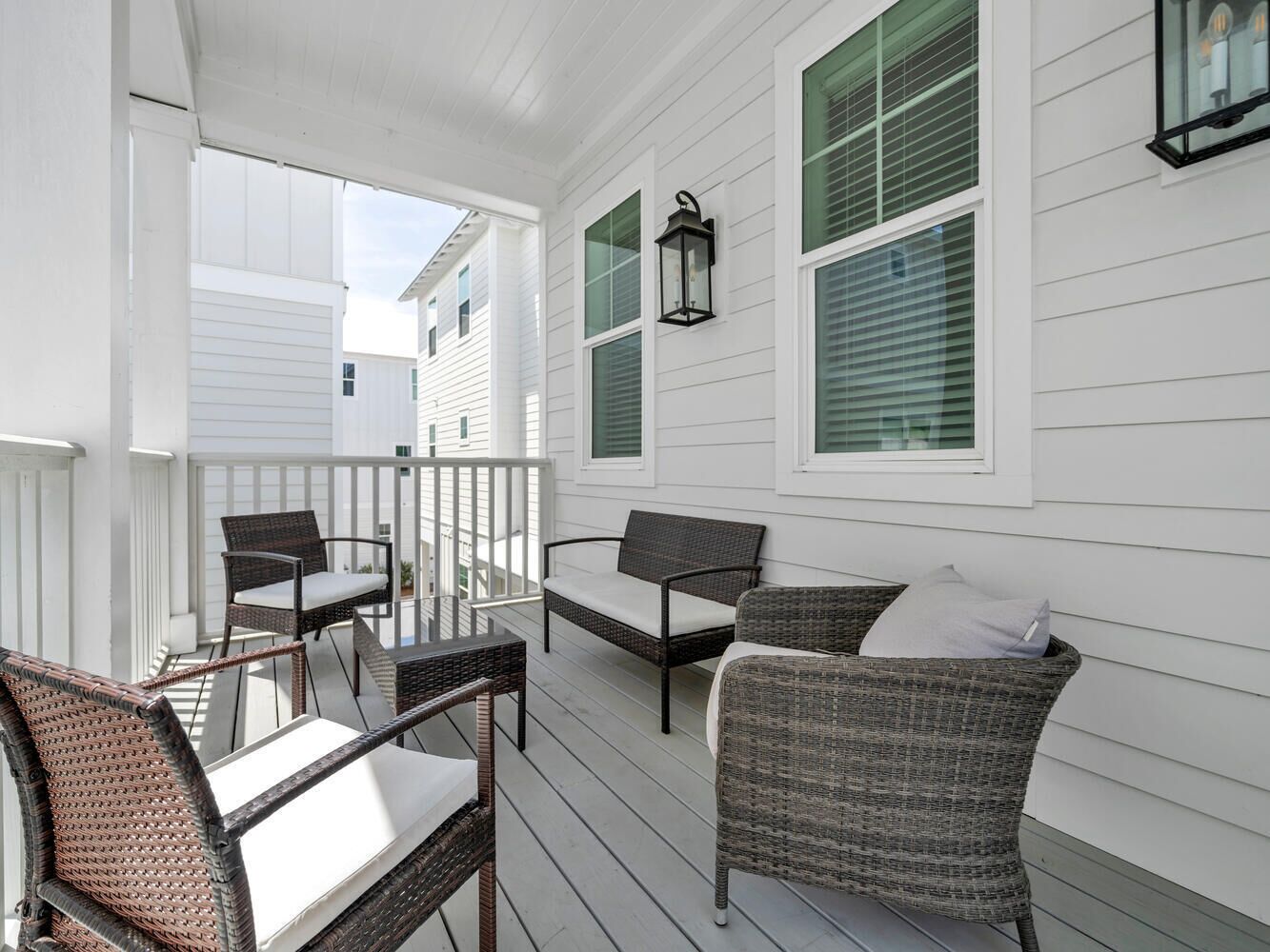 A covered porch with wicker furniture and a table, white siding, and green shutters.