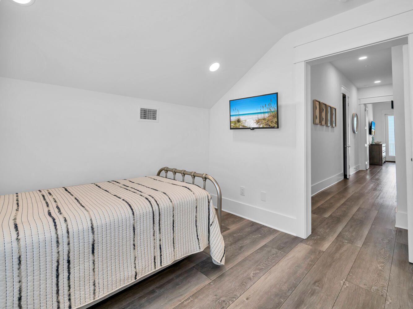 Quarto com cama, um quadro na parede e um corredor que leva a outro cômodo.