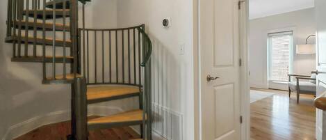 A staircase with a metal railing, a white door, and a wooden floor.