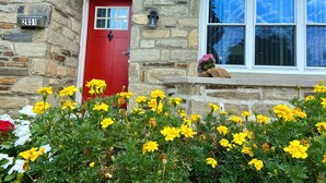 Une maison en pierre avec une porte rouge, portant le numéro 2031, et une fenêtre d’où l’on peut admirer le ciel.