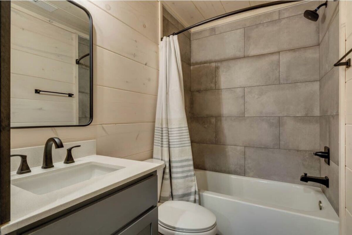 A bathroom with a white sink, a mirror, a toilet, and a bathtub.