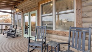 Une cabane en bois avec une véranda, des fauteuils à bascule et une table.