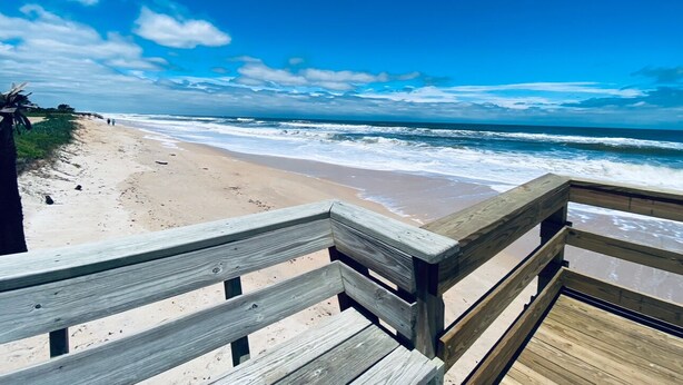A wooden boardwalk leading to a beach with waves crashing onto the shore. - Modern 4BR House Close to Beach & All Attractions (Palm Coast)
