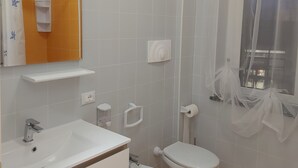 A bathroom with a white sink, two toilets, a mirror, and a shower curtain. - Apartment in the Orti area near the University (Alessandria)