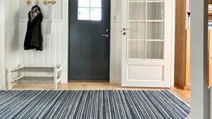 A room with a dark door, a white bench, a striped rug, and a bookshelf. - 4 Star Holiday Home in Byxelkrok (Byxelkrok)