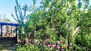 A garden with a variety of plants and flowers, a wooden structure, and a clear blue sky. - 8 Person Holiday Home in Jaegerspris (Jægerspris)