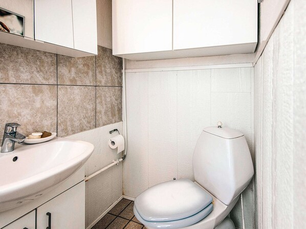 Une petite salle de bain avec un lavabo blanc, des toilettes et des murs carrelés.