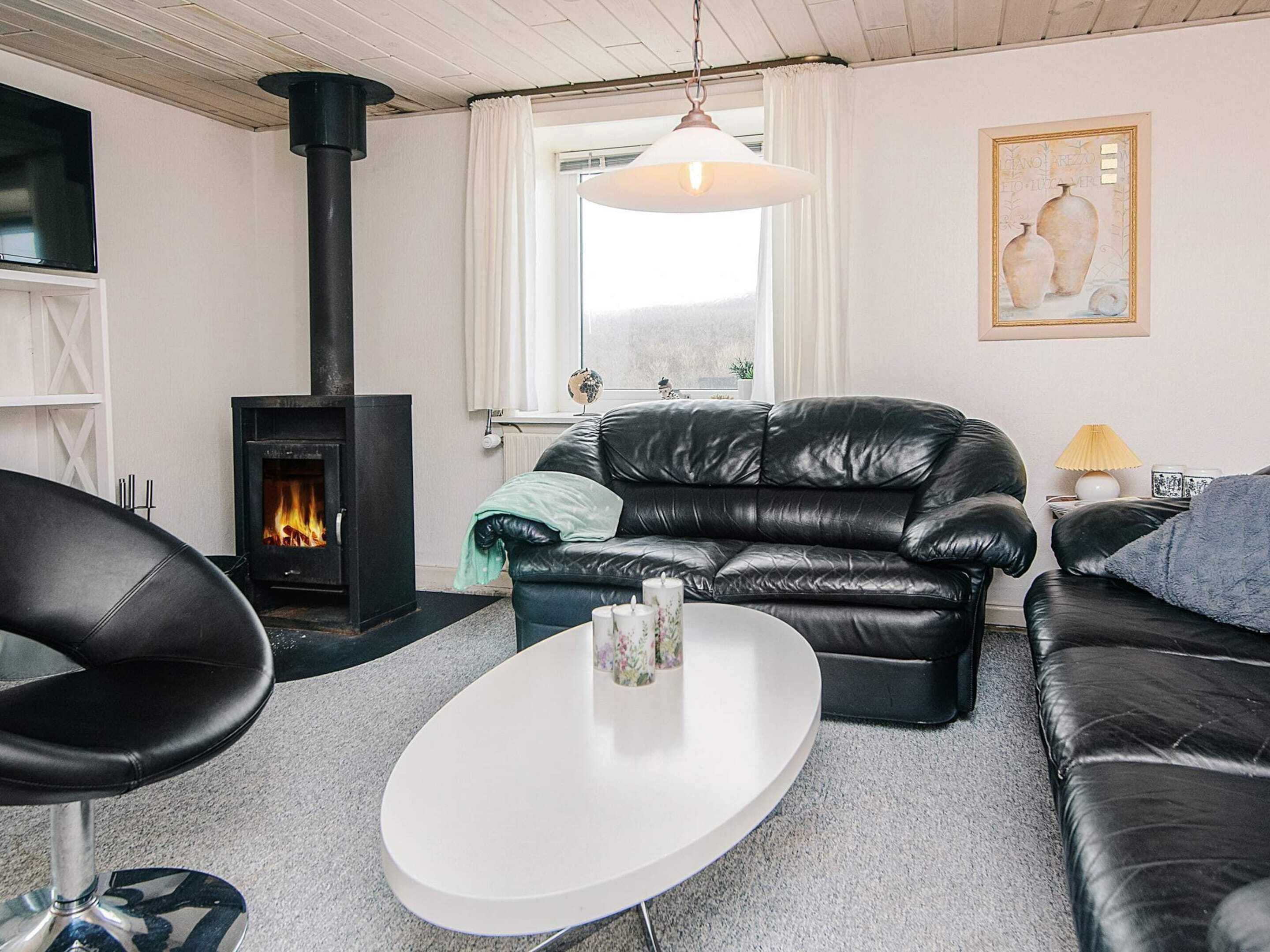 A living room with a fireplace, leather sofa, white coffee table, and a painting on the wall.