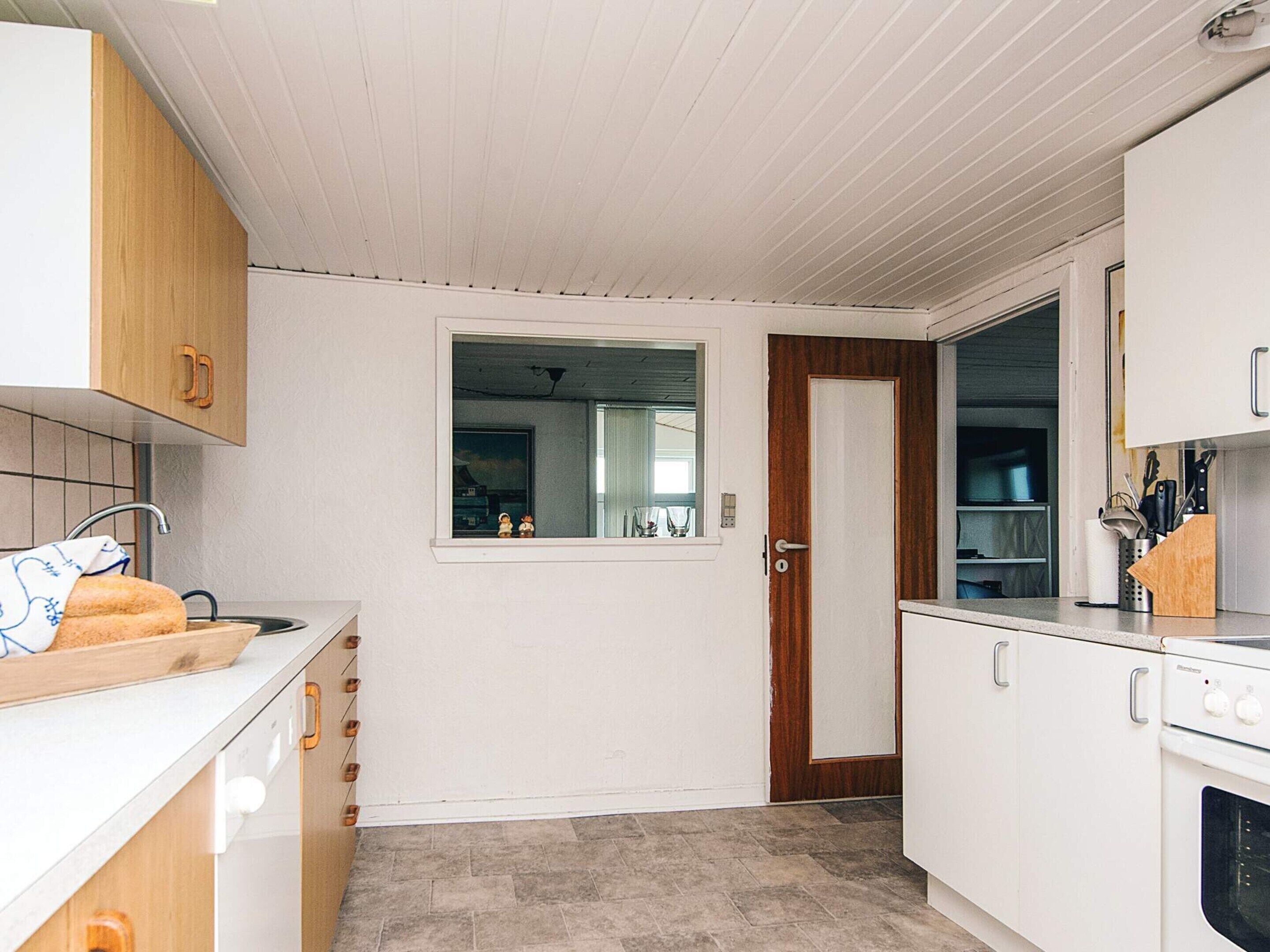 Eine kompakte Küche mit Holzausstattung, einem Einbauofen und einem Fenster mit Ausblick.