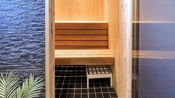 A wooden sauna bench with a tiled floor and a stone wall. - 4 Star Holiday Home in Ljungskile (Ljungskile)