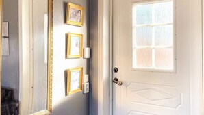 A white door with a small window and a decorative mirror with three framed pictures on the wall. - 4 Star Holiday Home in Ljungskile (Ljungskile)