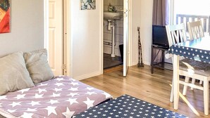 A cozy room with a bed, a dining table with chairs, a small kitchen area, and a window with curtains. - 4 Star Holiday Home in Ljungskile (Ljungskile)