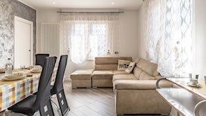 Ein modernes Wohnzimmer mit einer Eckcouch, einem Esstisch mit Stühlen und einer Küchenzeile.