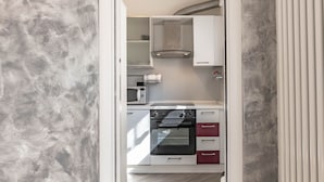 Eine kompakte Küche mit Mikrowelle, Backofen und weißen Schränken.