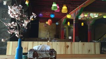A room with a wooden bench, a vase with flowers, and colorful hanging lights.