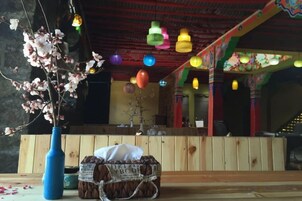 A room with a wooden bench, a vase with flowers, and colorful hanging lights.