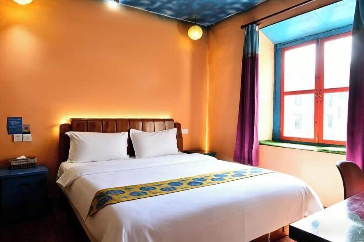 Ein Hotelzimmer mit einem Bett, einem Nachttisch, einem Tisch und einem Fenster mit Vorhängen.