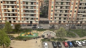 A multi-story residential building with balconies, a playground, and a parking area.
