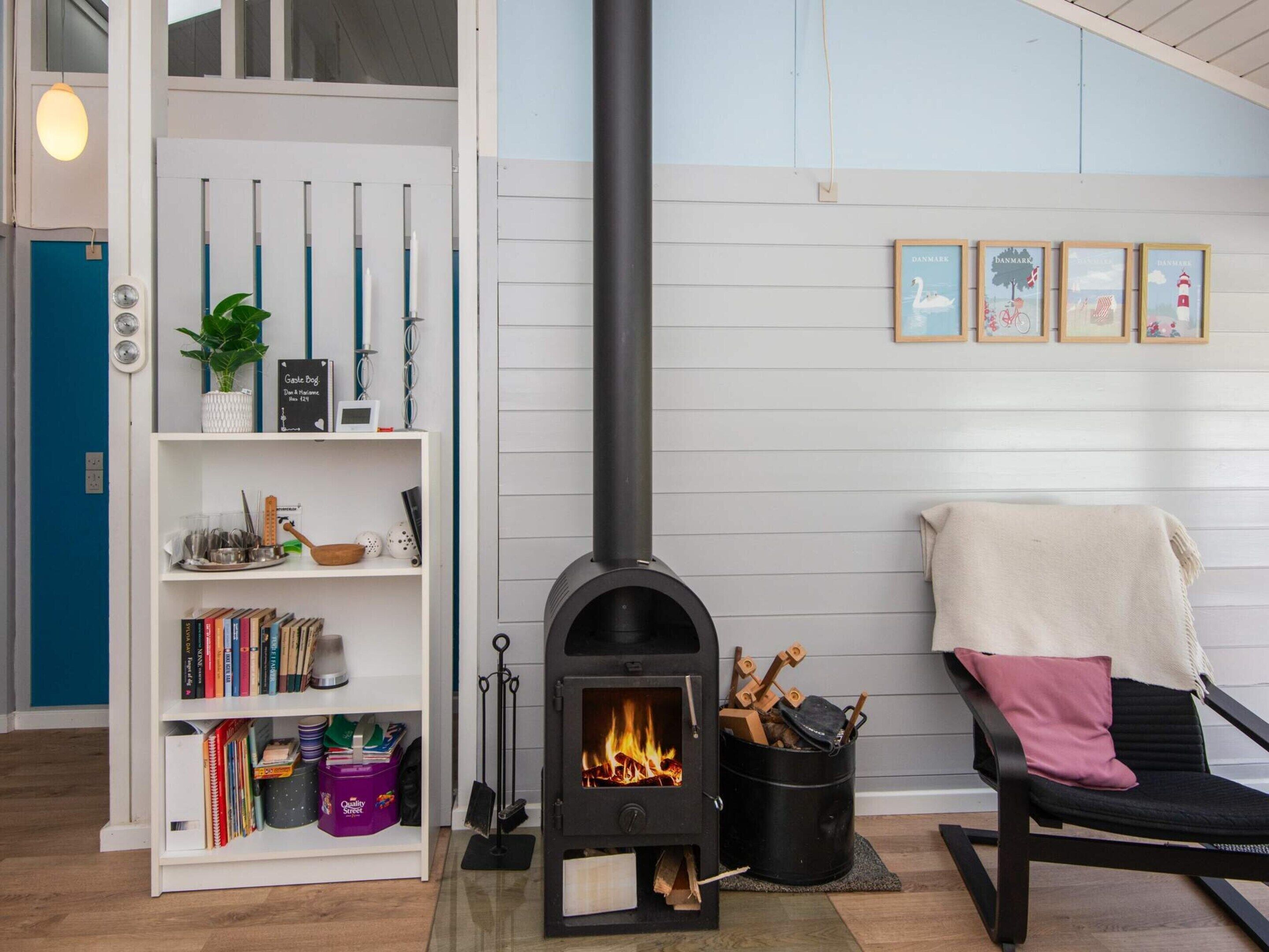 Une pièce chaleureuse avec un poêle à bois, une bibliothèque et un fauteuil avec une couverture.