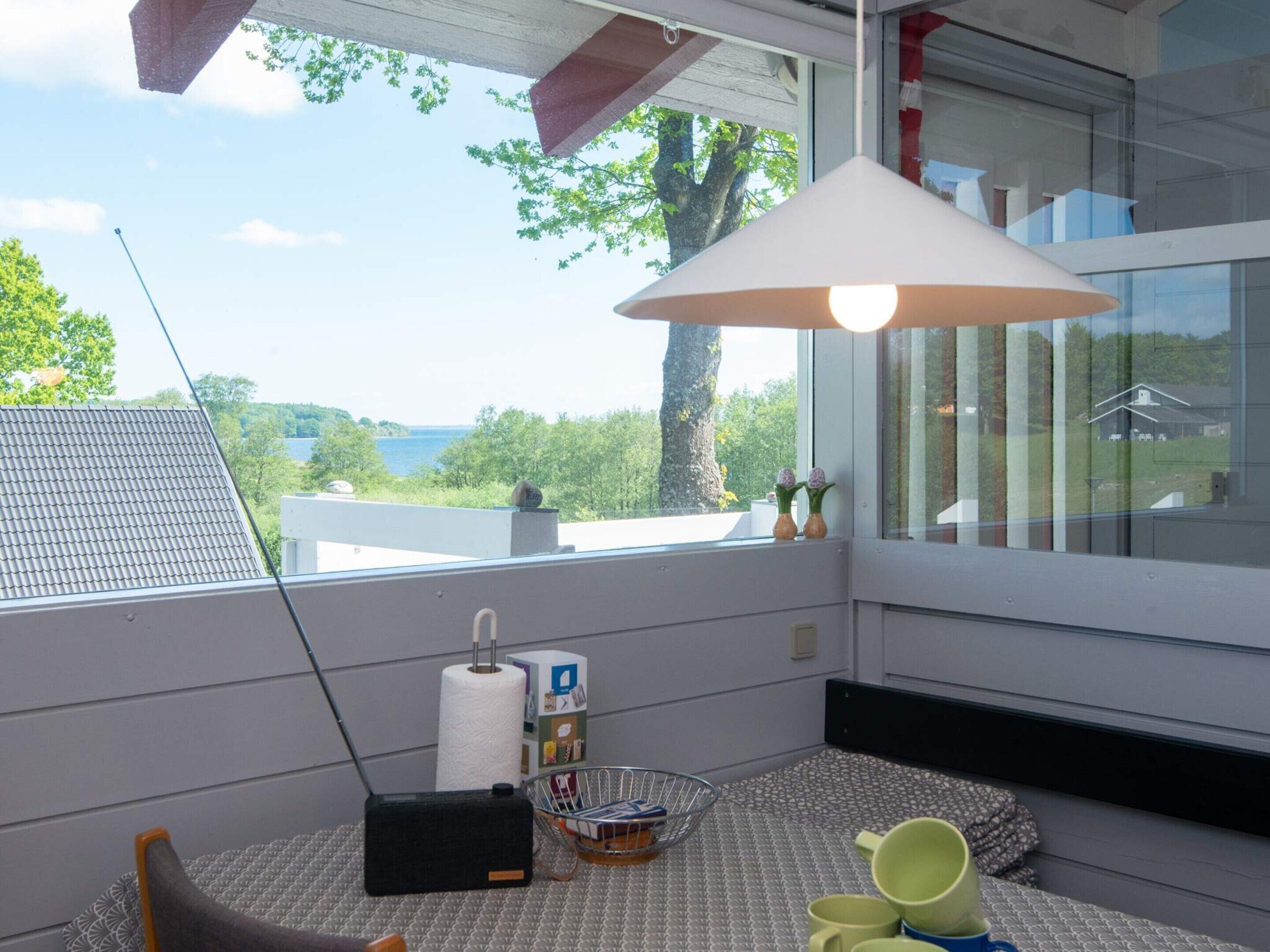 A modern room with a large window, a metal chair, a small table, and a hanging light fixture.