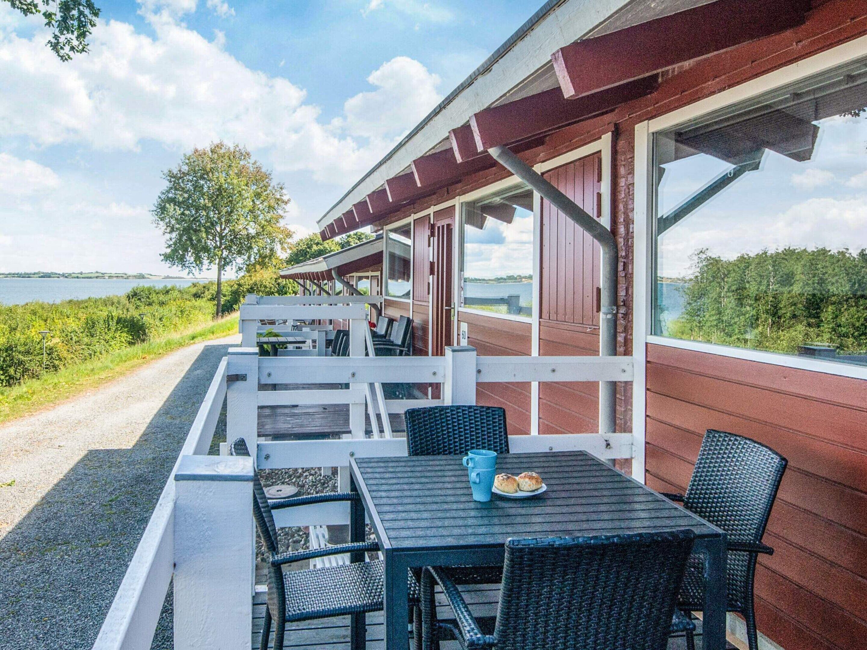 A covered outdoor seating area with tables and chairs, overlooking a body of water.