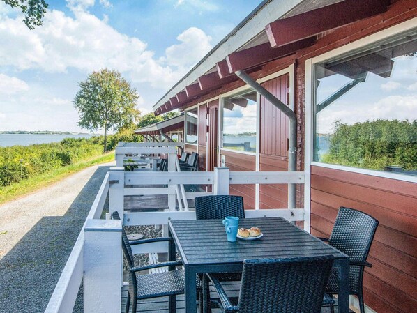 A covered outdoor seating area with tables and chairs, overlooking a body of water.