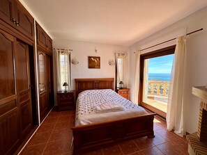 Relax in a spacious bedroom with a large bed and a stylish headboard, featuring a wardrobe, nightstand, and dresser.