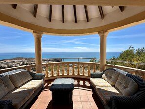 Relax in a tranquil outdoor seating area with a stunning sea view, surrounded by a balcony railing and comfortable seating.