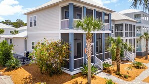 A two-story building with a balcony, surrounded by landscaped areas with palm trees and shrubs. - 30A Home: 3 King Suites, Bunk Room, Golf Cart & Bikes, Half Mile to Sand (Santa Rosa Beach)