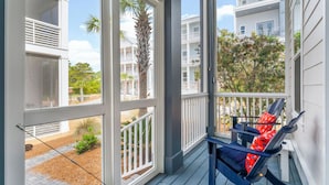 A porch with a view of a residential area, including a multi-story building and a palm tree. - 30A Home: 3 King Suites, Bunk Room, Golf Cart & Bikes, Half Mile to Sand (Santa Rosa Beach)