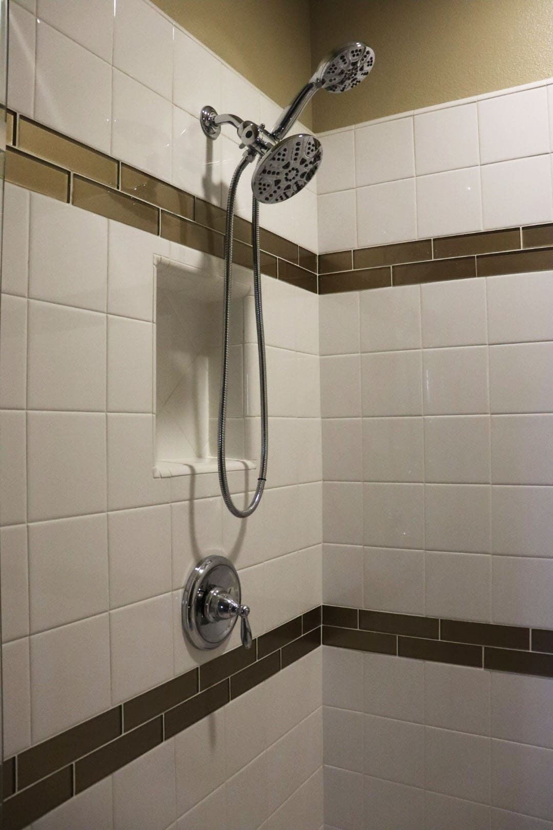 A corner shower with a handheld showerhead and a wall-mounted control valve.
