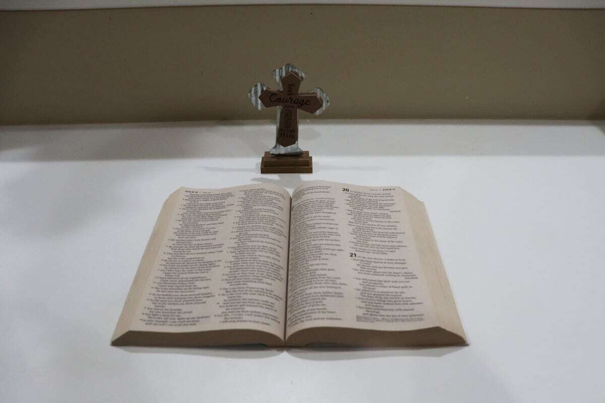An open book with a wooden cross on top.