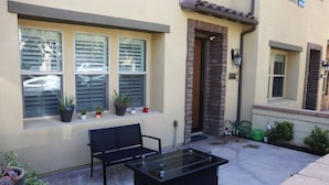A patio with a glass-top table, a black bench, and potted plants. - Pretty Relaxed Me: Pool, Spa, Clubhouse (Brea)