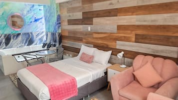 A modern hotel room with a bed, a desk, a chair, and a bathroom.