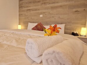 A neatly made bed with white linens, a fluffy white towel, and a decorative pillow. - Jacuzzi Spa Cusco Hotel (Cusco)