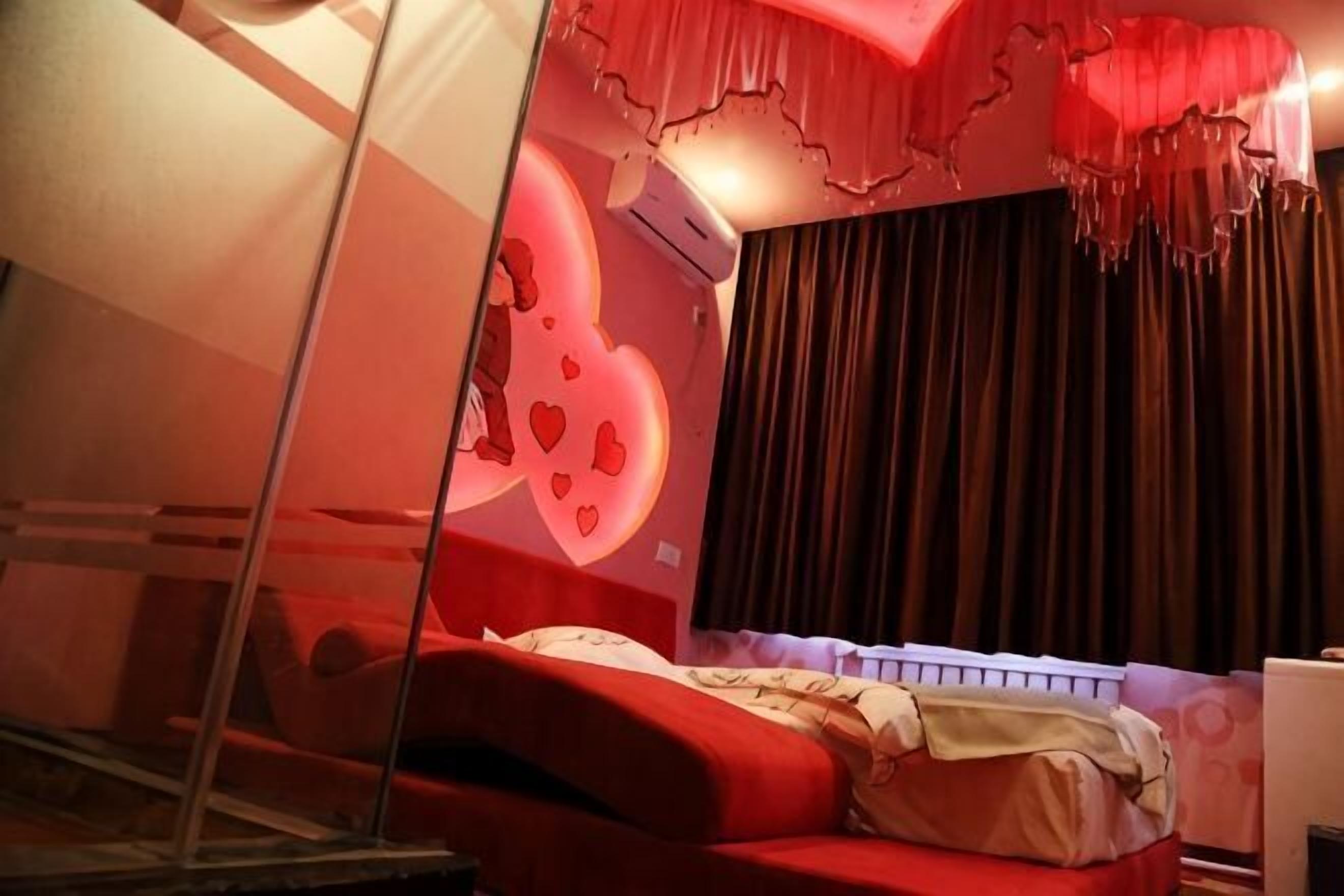 Una camera da letto con un divano rosso, un letto con testiera bianca e una parete decorata con un motivo a cuore.