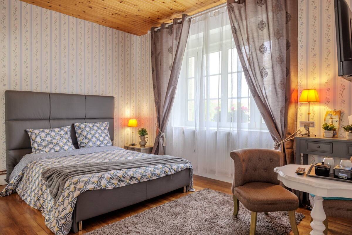 A bedroom with a bed, a chair, a desk, and a lamp.