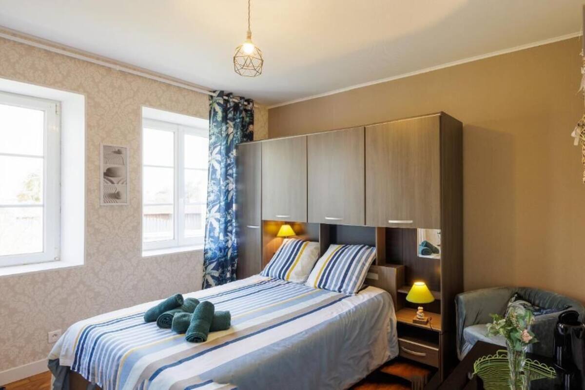 A bedroom with a bed, a wardrobe, a desk, and a chair.