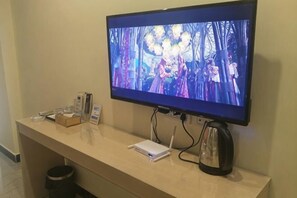 Una televisione montata a parete, una TV a schermo piatto, una macchina per il caffè, un quaderno e una scatola su un bancone in legno.