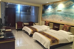 A hotel room with two beds, a desk, a chair, and a large painting of a beach scene. - Liuzhou Guihuang Hotel (Luzhai)