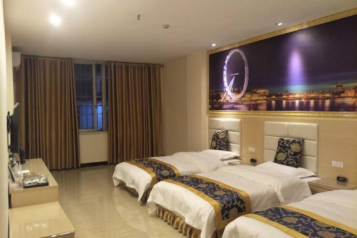 Una habitación de hotel con dos camas, un escritorio y un ventanal con cortinas.