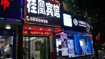 A building with a prominent sign for a hotel, a visible phone number, and a storefront with a sign for a mobile phone brand.