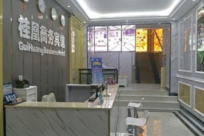 Un'area reception con un banco, sedie, un orologio e un cartello per l'Hotel GuiHuang Business.